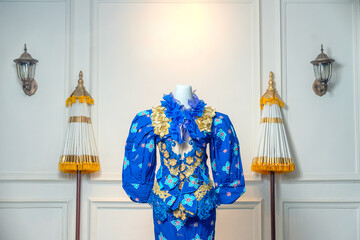 Stunning royal blue gown with puff sleeves, floral motifs, and gold lace accents, displayed against...