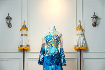 Elegant blue gown with intricate peacock embroidery and sheer sleeves, blending luxurious details...