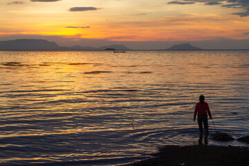 Silhouette of Woman with Crab Trap at Sunset in Kep