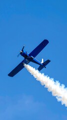 Blue airplane in the sky, smoke trail