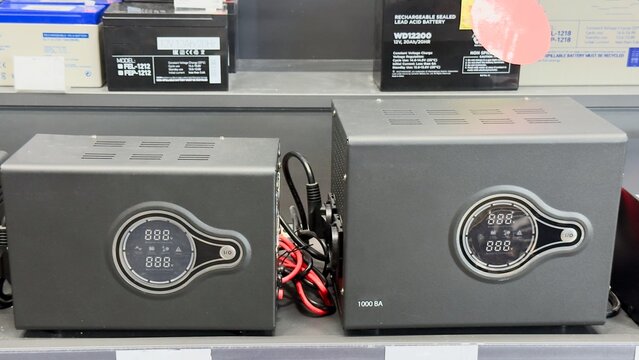 Battery chargers and sealed lead-acid batteries on a shelf &mdash; technical equipment for backup power systems, energy storage, and battery maintenance.