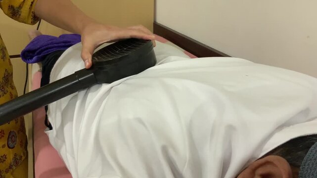 Senior man receiving Transcranial Magnetic Stimulation with nurse assistance