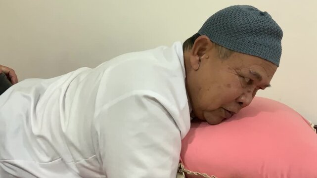 An elderly man undergoes Transcranial Magnetic Stimulation (TMS) therapy at a hospital, assisted by a professional nurse.