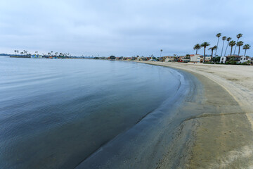 South shoreline curve of Sail Bay with sandy beaches and vacaction rental homes in summer, San Diego, California
