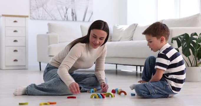 Mother and her son playing with toys on warm floor at home. Heating system