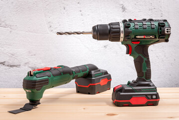 Cordless drill and electric multi-tool on wooden background