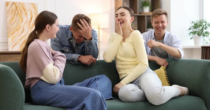Friends laughing on sofa indoors. Positive emotion