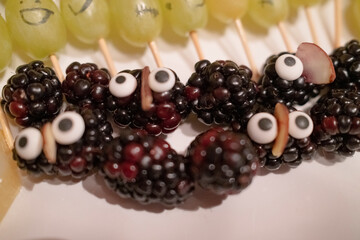 Creative and playful arrangement of blackberries with candy eyes, resembling cute creatures, set...
