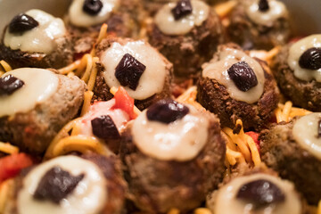 A delicious halloween platter featuring a mushroom topped with melted cheese and olives, served...