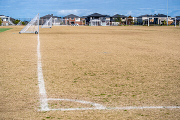 Multiple soccer goalposts on a dry grass sports field in suburban residential neighborhood. Point...