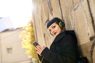 A young woman with a striking appearance listens to music through her headphones. She relaxes...
