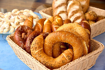 A variety of freshly baked pastries and bread are arranged in woven baskets, showcasing pretzels,...