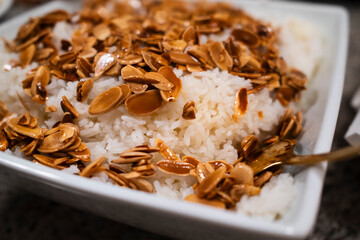 A delicious dish of fluffy white rice topped with golden-brown toasted almonds, adding a crunchy texture and nutty flavor