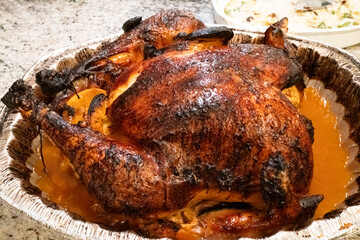 A beautifully roasted turkey, golden and crispy, resting in a tray with savory juices, perfect for a thanksgiving meal