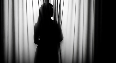 Silhouette of a woman standing behind curtains in a dark room expressing mystery and privacy and contemplating life in monochrome