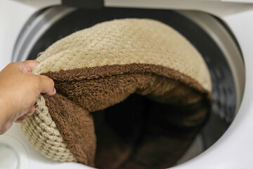 A black woman washing a dog bed cushion in a washing machine