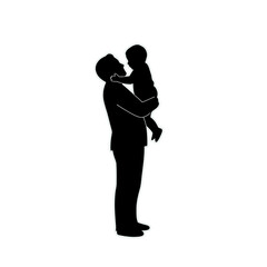 A tender silhouette of a father standing and lovingly lifting his young child.