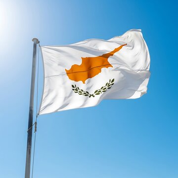 Cypriot flag waving against a clear blue sky. The white flag features the map of Cyprus in orange and olive branches below.