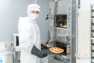 パン工場,食品工場で働く防塵服,クリーンスーツを着た製造スタッフの男性
