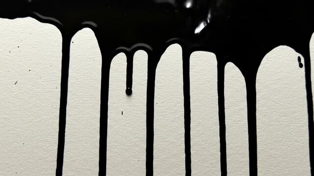 Black paint dripping down a white surface creating abstract patterns and textured background design art