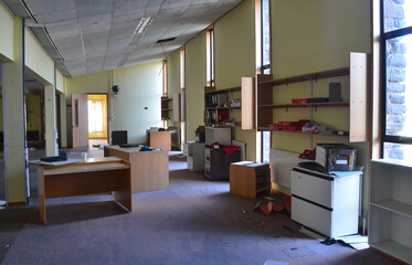 An abandoned, disheveled office space with scattered furniture and debris, signaling economic...
