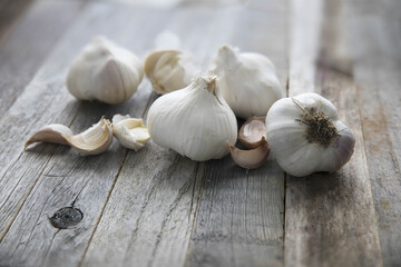 An assortment of fresh garlic bulbs and cloves on a rustic wooden surface. Ideal for showcasing healthy, organic, real food ingredients for diet-conscious cooking and restaurants