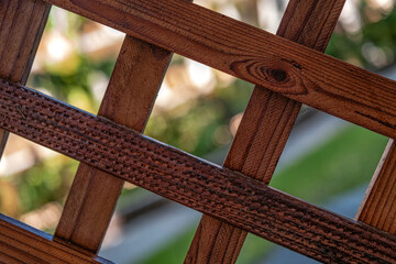 Closeup of a Burnt Sienna Redwood Lattice with a Blurred Background.