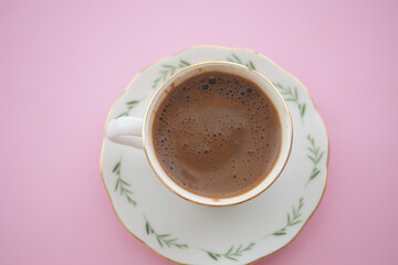 Warm coffee cup on delicate plate with pink background
