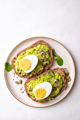 Top view of Avocado toast with boiled egg, sunflower seeds, pumpkin seeds and sesame seeds on plate, Healthy eating