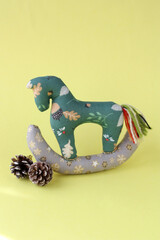 Cristmas 2026: fabric horse for Christmas. Christmas tree decoration, gift for a child. Vertical photo. Yellow background.