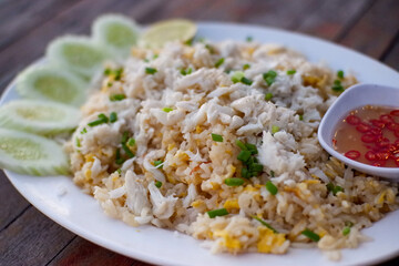 Thai style fried rice with pork, cucumber with chili in fish sauce in small cup on plate, Thai food.