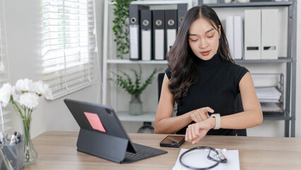 A woman is sitting at a desk with a laptop and a cell phone