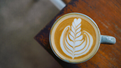 A close-up view of a cup of coffee with intricate latte art in the shape of a leaf
