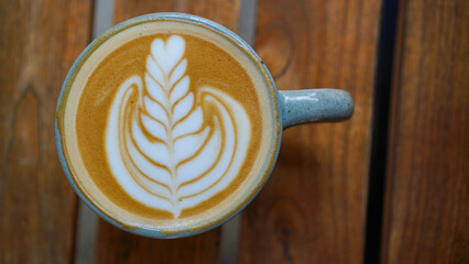 A close-up view of a cup of coffee with intricate latte art in the shape of a leaf