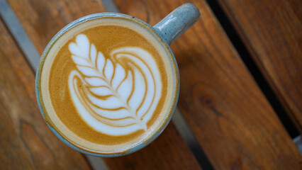A close-up view of a cup of coffee with intricate latte art in the shape of a leaf