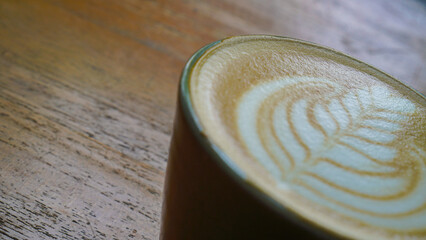 A close-up view of a cup of coffee with intricate latte art in the shape of a leaf