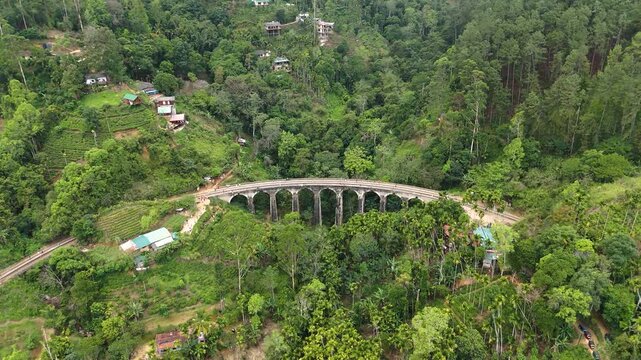 Aerial 4K drone footage of the iconic Nine Arch Bridge near Ella, Sri Lanka. Stunning views of the historic railway viaduct, lush green hills, and scenic train crossing for travel and tourism projects