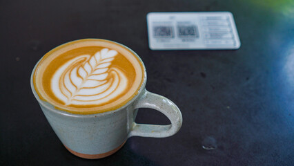 A close-up view of a cup of coffee with intricate latte art in the shape of a leaf