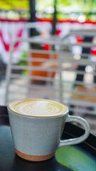A close-up view of a cup of coffee with intricate latte art in the shape of a leaf