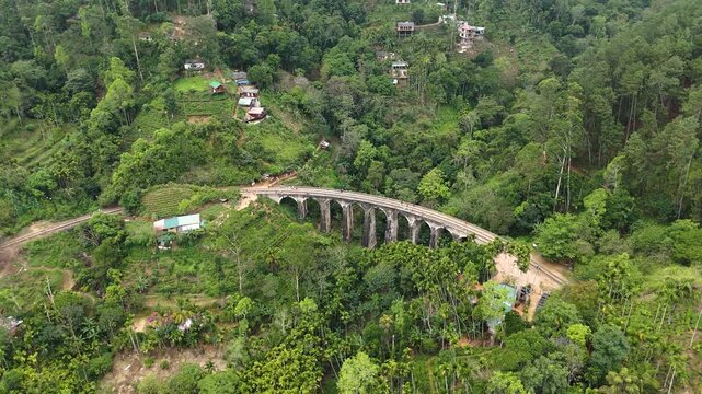 Aerial 4K drone footage of the iconic Nine Arch Bridge near Ella, Sri Lanka. Stunning views of the historic railway viaduct, lush green hills, and scenic train crossing for travel and tourism projects