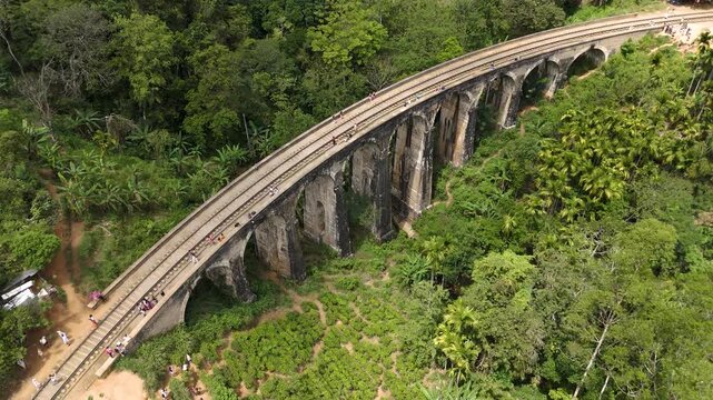 Aerial 4K drone footage of the iconic Nine Arch Bridge near Ella, Sri Lanka. Stunning views of the historic railway viaduct, lush green hills, and scenic train crossing for travel and tourism projects