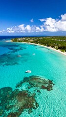 Obraz premium Aerial view of a tropical coast, showcasing turquoise water, a sandy beach, and several boats anchored near a vibrant coral reef