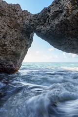 Formação rochosa única na costa de Curaçao, com ondas do mar do Caribe passando sob uma...