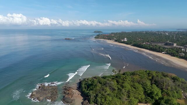 Aerial 4K drone footage of Bentota Beach, Sri Lanka. Beautiful tropical coastline, golden sands, palm trees, and turquoise waters ideal for travel, tourism, beach, and tropical vacation projects.