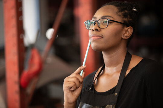 Confident african american female worker holding blue folder while inspecting car parts warehouse. Concept of automotive maintenance, quality control industrial service.