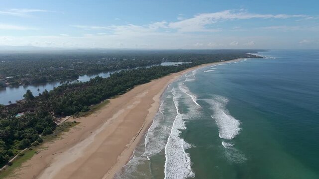 Aerial 4K drone footage of Bentota Beach, Sri Lanka. Beautiful tropical coastline, golden sands, palm trees, and turquoise waters ideal for travel, tourism, beach, and tropical vacation projects.