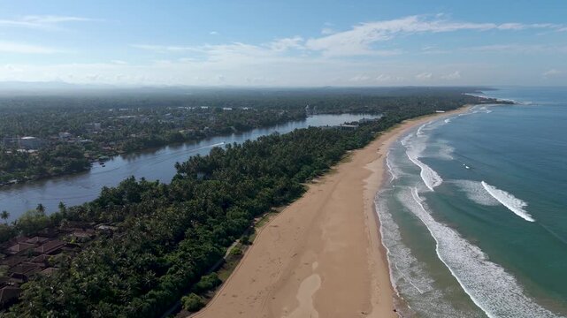 Aerial 4K drone footage of Bentota Beach, Sri Lanka. Beautiful tropical coastline, golden sands, palm trees, and turquoise waters ideal for travel, tourism, beach, and tropical vacation projects.