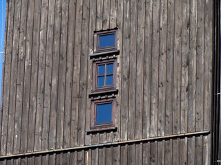 A modern, minimalist wooden building facade with small vertically aligned rectangular windows under...