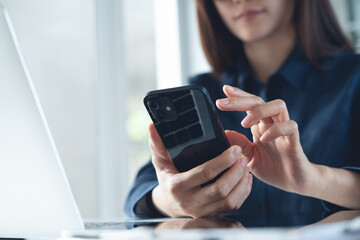Business woman using mobile phone and working on laptop computer with digital tablet on office table. Businesswoman surfing the internet, social networking via smartphone, closeup