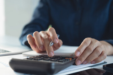 Close up woman hand using calculator to calculate home finance and writing note, accounting on...